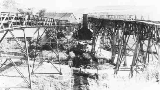 Die alte Holzbrücke für die Kleinbahn, das alte Spritzenhaus am Dorfeingang, die neue Gummibandtransportanlage ca. 1949/50